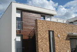 Na zdjęciu przykład projektu domu w nowoczesnym stylu osiągnięty poprzez połączenie geometrycznych brył o płaskich dachach, oraz elewacji drewnianej z kamieniem.